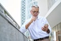 Older senior business man holding mobile phone using cellphone outdoor. Royalty Free Stock Photo