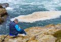 Older and retired man preparing his fishing rod and hooks laying on the cliff of the fishing village of Rinlo