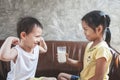 Older sister giving a glass of milk to her young brother and he is smiling and making strong body gesture