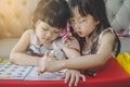 Older sister teaching her younger sister drawing, writing , learning and doing the homework at home. education and family concept.