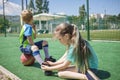 Older sister ties laces on boots to his brother during game on football field, fan support, sports