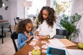 Older sister wearing white sweater helping her little sister studying letters