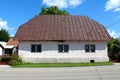 Older small urban family house on concrete foundation with dilapidated white facade around old windows covered with rusted old Royalty Free Stock Photo