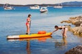 Older teenage girl helps little sister go to sea on sup board