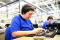 older woman assembles electronic components in a hi tech factory