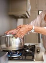 Older woman boiling water in pot on stove top Royalty Free Stock Photo