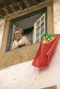 An older woman celebrates soccer victory by hanging Portuguese flag out the window of Tomar, Portugal