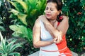 Older woman clutching her elbow in pain while sitting in the park, health concept