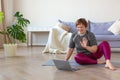 An older woman communicates with a trainer online before a Pilates workout.