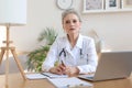 Older woman doctor therapist wearing headset video call talking to web camera consulting virtual patient online Royalty Free Stock Photo