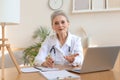 Older woman doctor therapist wearing headset video call talking to web camera consulting virtual patient online Royalty Free Stock Photo