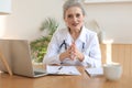 Older woman doctor therapist wearing headset video call talking to web camera consulting virtual patient online Royalty Free Stock Photo