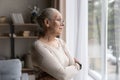 Older woman in glasses lost in thoughts looking out window Royalty Free Stock Photo