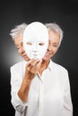 Older woman hiding happy and sad face behind mask Royalty Free Stock Photo