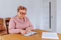 An older, overweight woman reading a book with glasses on while sitting comfortably at home. Royalty Free Stock Photo