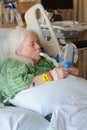 Older woman in hospital bed using incentive spirometer