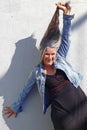 An older woman laughing stretches her very long gray hair upwards