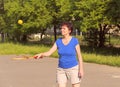 Older woman plays with a tennis ball and racket