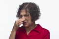 Older woman plugs her nose, horizontal