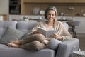 Older woman relaxing on couch reading a favorite book Royalty Free Stock Photo