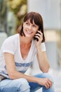 Older woman sitting outside talking on mobile phone in city Royalty Free Stock Photo