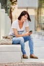 Older woman smiling sitting with mobile phone outside Royalty Free Stock Photo