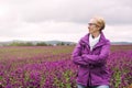 Older woman standing at field of purple flowers and enjoying the Royalty Free Stock Photo