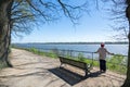 Older woman stands on the Elbe bank and looks into the distance