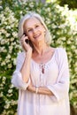 Older woman talking on mobile phone outside in garden Royalty Free Stock Photo