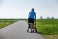 An older woman with a walker to help her to walk outside in nature.