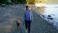 Older woman walking at the beach with her dog.