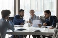 Older and young businesspeople gathered in boardroom discuss financial statistics