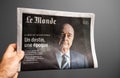 Olding against gray background Le Monde newspaper with special edition