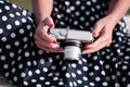 Oldschool mirrorless camera in the hands of a girl in a white and black dot dress