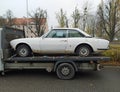 Old rusty classic white Peugeot 504 coupe on a trailer