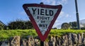 Oldy yield sign Ireland on Irish road with green grass, stone