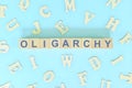 Oligarchy government form concept. Wooden blocks typography flat lay in blue background. Royalty Free Stock Photo