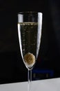 Olive in a champagne glass covered with bubbles on a dark background, close-up Royalty Free Stock Photo