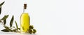 Olive fresh extra virgin oil in a glass bottle and green olives with leaves on white background.