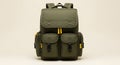 Olive green backpack with yellow accents standing upright on light beige background showcasing multiple compartments and modern Royalty Free Stock Photo