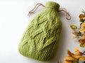 olive green knitted hot water bottle cover with a cable knit pattern, displayed on a rustic surface Royalty Free Stock Photo
