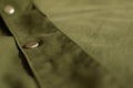 Olive green military uniform with metal button background, close up, copy space