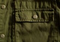 Olive green military uniform pocket with metal button, close up