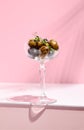 Olive Kalamata in cocktail glass. Black and green olives food on white table with pink wall. Day sunlight with hard shadow of fern Royalty Free Stock Photo