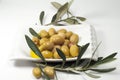 Olive leaves, olives on a white plate.