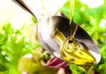 Olive oil being poured into a spoon and salad Royalty Free Stock Photo