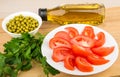 Olive oil in bottle, tomatoes, green peas and parsley