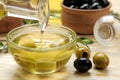Olive oil and green and black olives in a wooden bowl on a natural wooden table. close-up Royalty Free Stock Photo