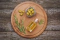 Olive oil and green olives in bowl on wooden board over wooden background, top view. Greek oil and olives concept