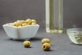 Olive oil pouring from bottle in bowl and fresh olives in ceramic plate Royalty Free Stock Photo